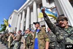 FILE - Maidan self-defense activists shout slogans in front of the Ukrainian parliament building in Kyiv on July 1, 2014, as they call for the ratification of an agreement with the European Union.