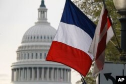 The French flag, along with the American flag and the flag of the District of Columbia, is seen with the U.S. Capitol in the distance in advance of French President Emmanuel Macron's Washington arrival for a state visit, April 23, 2018.
