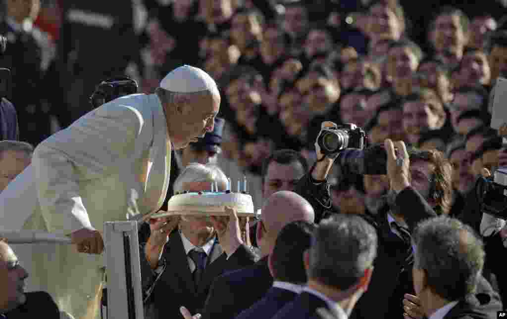 Pope Francis blows out candles on a birthday cake on the occasion of his 78th birthday as he arrives for his weekly general audience in St. Peter's Square at the Vatican.