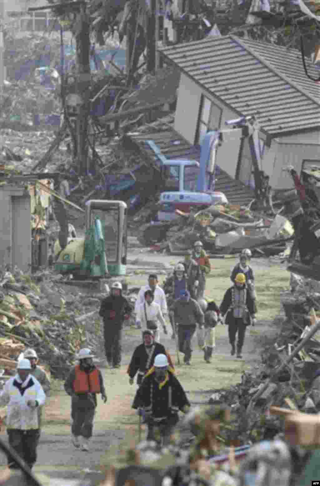 CORRECTS SOURCE - In this March 13, 2011 photo, rescue workers and tsunami survivors flee through rubble for the higher place upon hearing a tsunami warning in Rikuzentakata in Iwate Prefecture, northeastern Japan, Sunday, March 13, 2011, two days after a