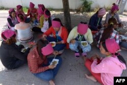 រូបឯកសារ៖ កម្មករ​រោងចក្រ​កាត់​ដេរ​សម្លៀកបំពាក់​កម្ពុជា​កំពុង​ទទួល​ទាន​អាហារ​ពេល​ថ្ងៃ​ត្រង់​នៅ​ក្រោម​ដើម​ឈើ​មួយ​ដើម នៅ​ខាង​មុខ​រោងចក្រ​ដែល​ពួកគេ​ធ្វើការ ភ្នំពេញ ថ្ងៃទី៨ ខែឧសភា ឆ្នាំ២០១៤។