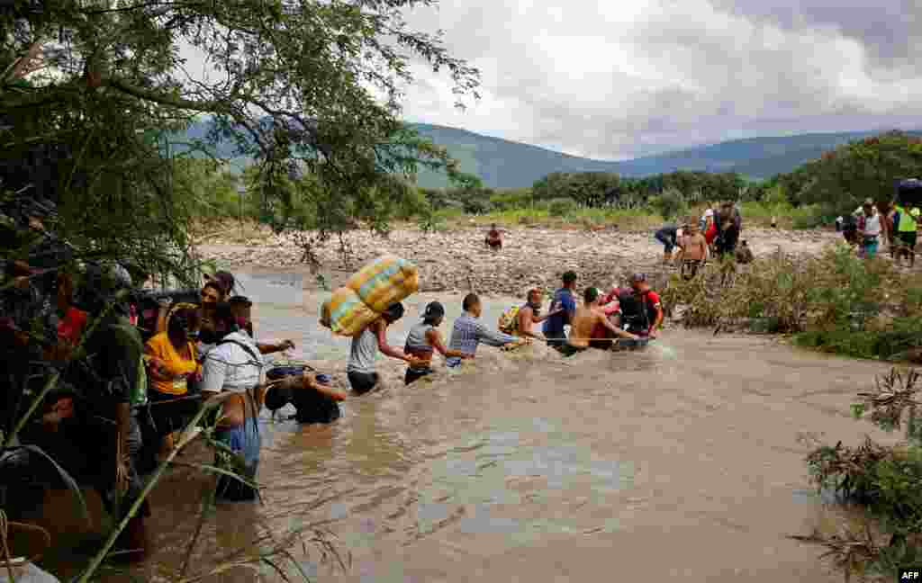 Migrants use a rope to cross the Tachira River, the natural border between Colombia and Venezuela, as the official border remains closed due to the COVID-19 pandemic in Cucuta, Colombia, Nov. 19, 2020. 