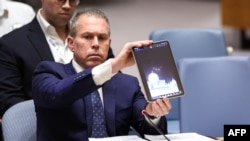 FILE - Israeli Ambassador to the U.N. Gilad Erdan shows a video of drones and missiles heading toward Israel during a U.N. Security Council meeting at U.N. headquarters in New York City, April 14, 2024.