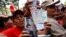 FILE - Pro-government supporters cheer as some hold up new banknotes and patriot identification cards during a rally in Caracas, Venezuela.