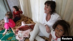 UNHCR's Representative in Lebanon Ninette Kelley sits with Syrian refugee children inside a makeshift room during her visit to the refugees on the occasion of the World Refugee Day, in Alman town, in the Shouf area in Mount Lebanon, Lebanon, June 20, 2013