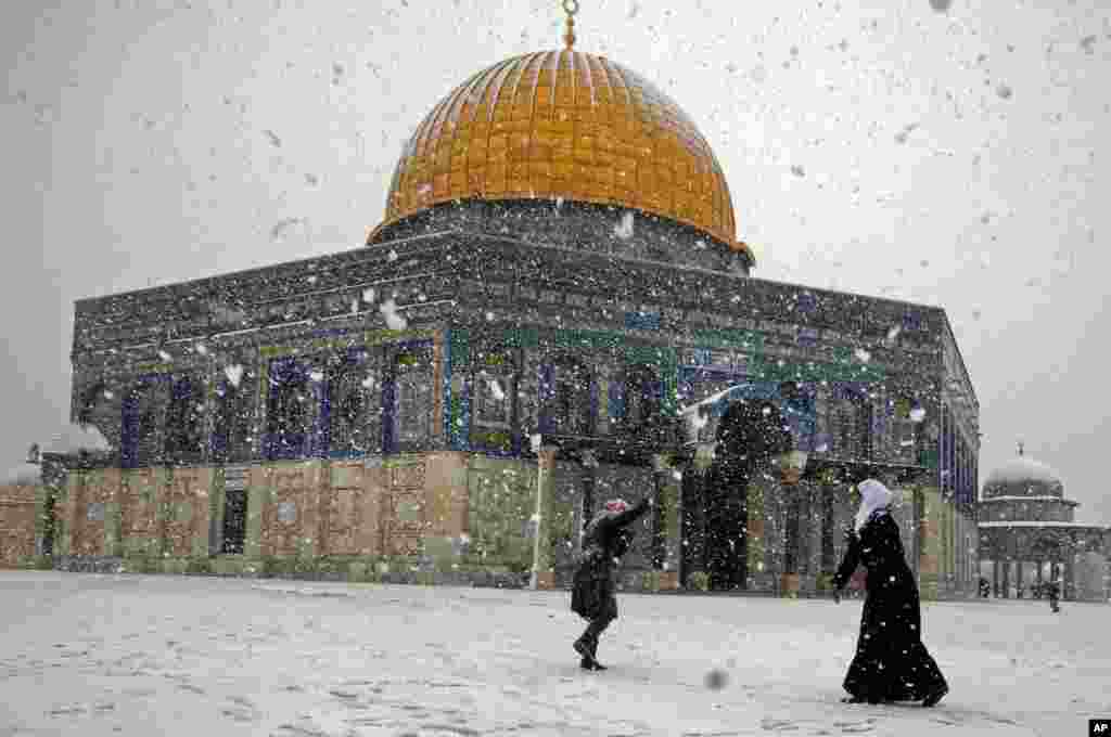 Two Palestinian women play with snow outside the Dome of the Rock in Jerusalem, Dec. 12, 2013.