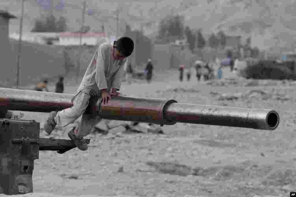 An Afghan child plays on the barrel of a Soviet tank in the Behsood district of Jalalabad, Afghanistan.