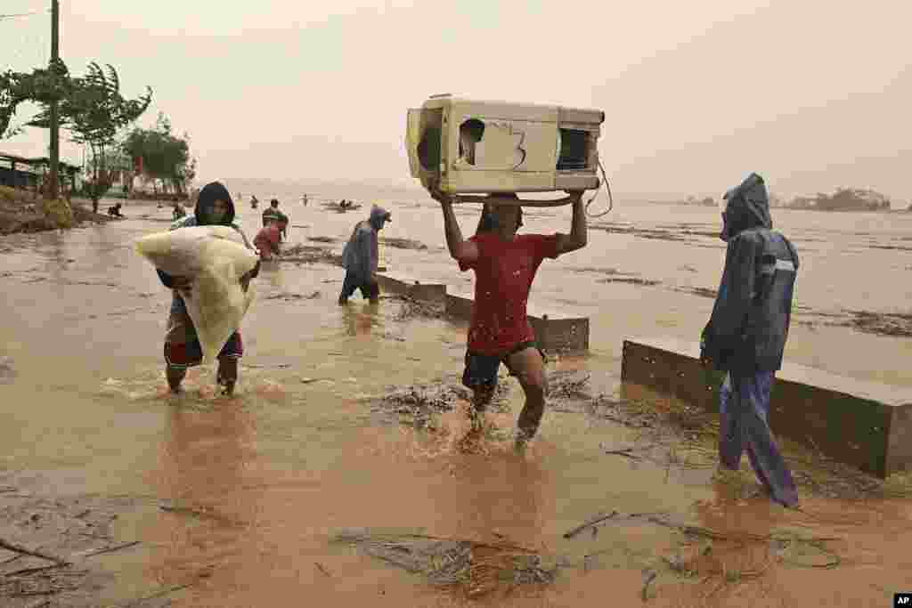 Warga membawa barang-barang mereka saat sungai meluap, menyusul hujan lebat akibat Topan Toraji di Kota Ilagan, provinsi Isabela, Filipina utara Senin, 11 November 2024. (AP)&nbsp;