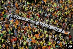 People hold a banner reading 'Independence now' as they gather for a rally to show support for a Catalan independent nation and the right to vote in a controversial referendum that has been banned by Spain, Sept. 11, 2017.