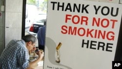 FILE - A man has his lunch behind a poster demarcating a No-Smoking zone in Singapore, June 28, 2006. 