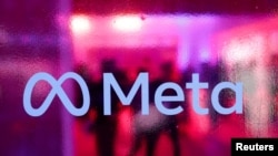 FILE—People walk behind a Meta Platforms logo during a conference in Mumbai, India, September 20, 2023.