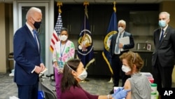 FILE - President Joe Biden, left, accompanied by officials, visits a COVID-19 vaccination site at the VA Medical Center in Washington, D.C., March 8, 2021.