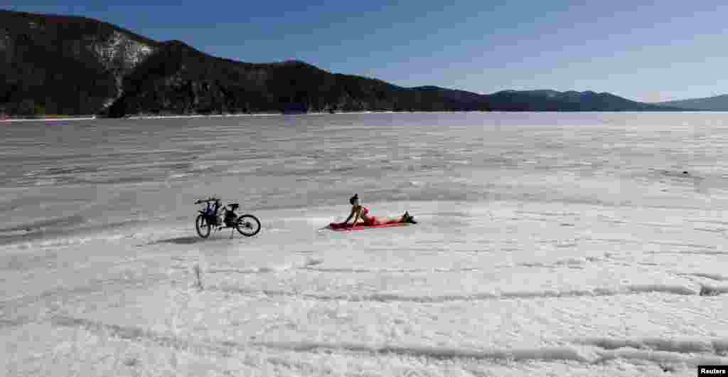 A woman enjoys the sun on the banks of the Yenisei River, with the air temperature at about 13&deg; C (55.4&deg; F), in the Taiga district outside Russia&#39;s Siberian city of Krasnoyarsk.