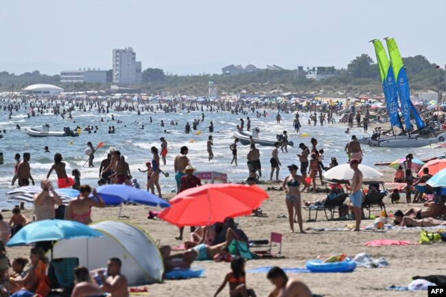 People bathe at a beach during a heat wave in La Grande Motte, southern France, on July 10, 2023. (Photo by Sylvain THOMAS / AFP)