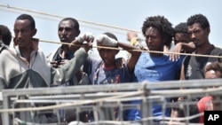 FILE - Migrants wait to disembark from a ship at Catania harbor, Italy, June 16, 2015. 