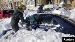24일 미 동부 뉴저지 주 유니온 시에서 주민들이 자동차 위에 쌓인 눈을 치우고 있다.