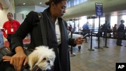 Milsa Grant of New York holds her dog Lulu Madonna, as she waits to check-in at LaGuardia Airport in New York. (File photo)