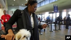 Milsa Grant of New York holds her dog Lulu Madonna, as she waits to check-in at the Delta terminal at LaGuardia Airport in New York. Apps can help plan and navigate new places and languages while you travel. (FILE, AP Photo/Dima Gavrysh)