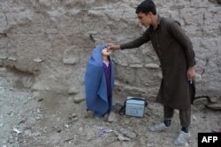 FILE - An Afghan health worker administers the polio vaccine to a child during a vaccination campaign on the outskirts of Jalalabad on March 12, 2018.