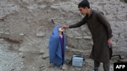 An Afghan health worker administers the polio vaccine to a child during a vaccination campaign on the outskirts of Jalalabad on March 12, 2018.