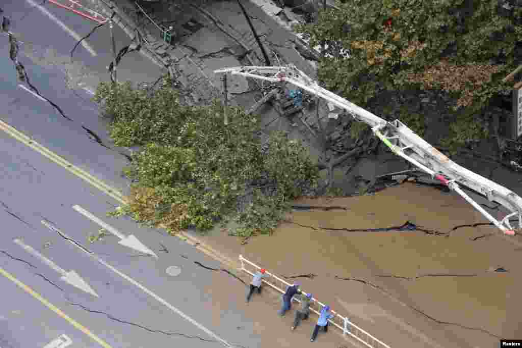 Workers remove barrier from a cave-in site on a road in Hangzhou, Zhejiang province, China, Aug. 28, 2019.