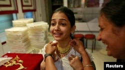 Girl tries on gold necklace inside jewelry showroom in Mumbai, Apr. 16, 2013.