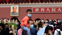 In this May 3, 2021, file photo, a man and child wearing masks visit Tiananmen Gate near the portrait of Mao Zedong in Beijing. (AP Photo/Ng Han Guan, File)