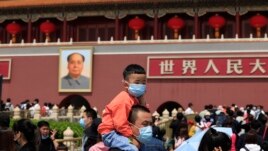 In this May 3, 2021, file photo, a man and child wearing masks visit Tiananmen Gate near the portrait of Mao Zedong in Beijing. (AP Photo/Ng Han Guan, File)