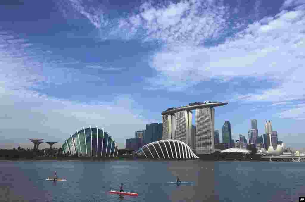 People kayak in front of the skyline of the Marina Bay in Singapore.