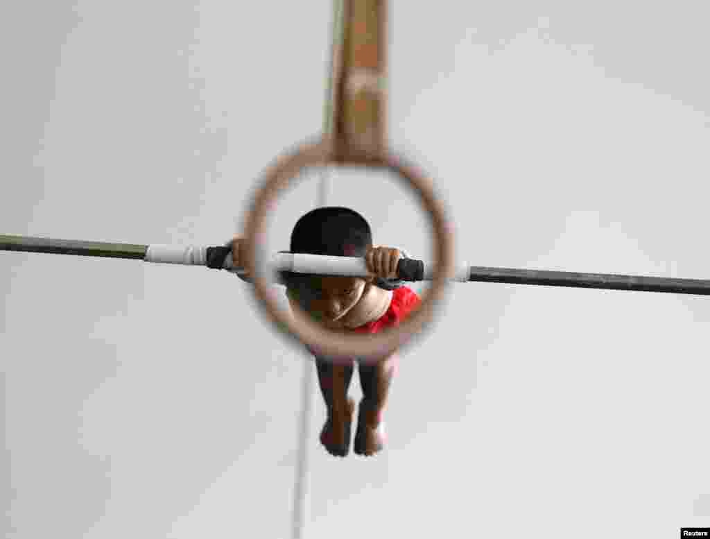 A six-year-old gymnast practices on a horizontal bar at the gymnastics hall of a sports school in Jiaxing, Zhejiang province, China.