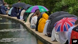 People hold umbrellas as take shelter after rain delayed play on day eight of the Wimbledon Tennis Championships in London, Tuesday, July 6, 2021. (AP Photo/Kirsty Wigglesworth)