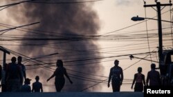 Residentes caminan frente a una columna de humo durante la escasez de combustible en Puerto Príncipe, Haití, el 26 de octubre de 2021. 