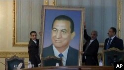 Officials remove a portrait of ousted Egyptian President Hosni Mubarak at the main Cabinet building in Cairo, February 13, 2011