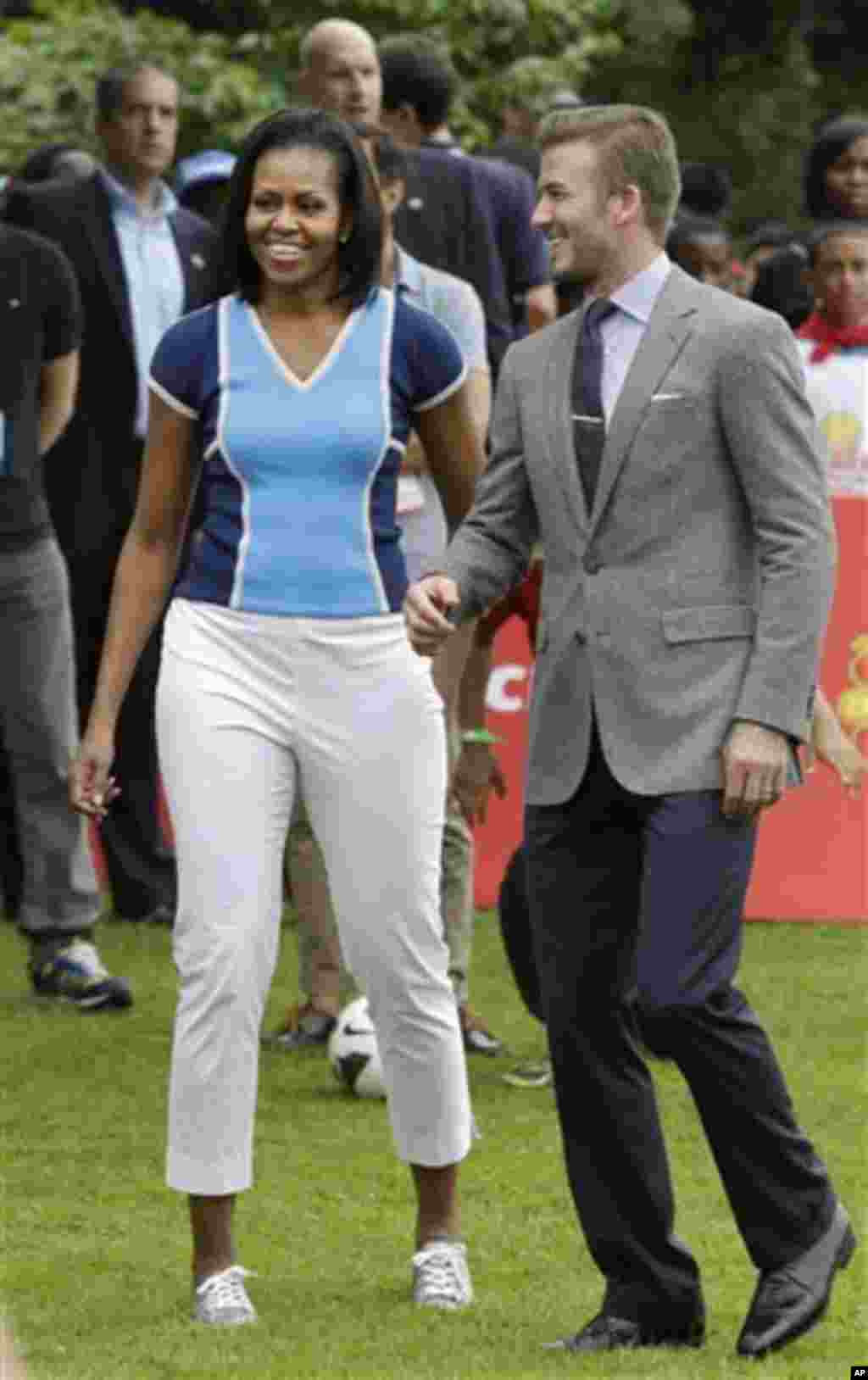 U.S. first lady Michelle Obama, left, walks with soccer player David Beckham during a 'Let's Move!' event for about 1,000 American military children and American and British students at the U.S. ambassador's residence in London, ahead of the 2012 Summer O