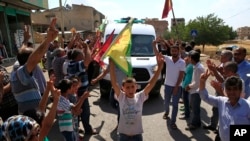 Supporters of Kurdish forces line the road as the convoy carrying the body of U.S. citizen Keith Broomfield, killed fighting militants of the Islamic State group in Kobani, passes through Suruc on the Turkey-Syria border, June 11, 2015.