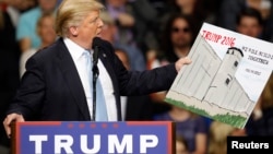 Republican presidential candidate Donald Trump holds a sign supporting his plan to build a wall between the United States and Mexico at his campaign rally in Fayetteville, North Carolina earlier this year. (Reuters/file)