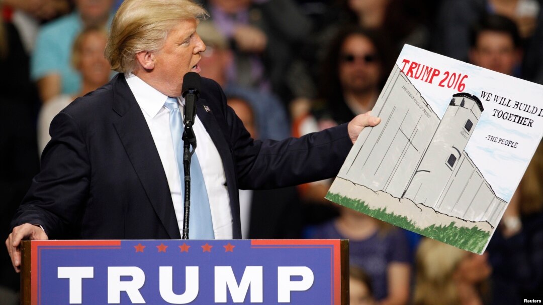 Republican presidential candidate Donald Trump holds a sign supporting his plan to build a wall between the United States and Mexico at his campaign rally in Fayetteville, North Carolina earlier this year. (Reuters/file)