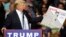 FILE - U.S. Republican presidential candidate Donald Trump holds a sign supporting his plan to build a wall between the United States and Mexico that he borrowed from a member of the audience at his campaign rally in Fayetteville, North Carolina, March 9, 2016.