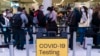 File-Travelers wait for screening on November 24, 2021 near the sign on the COVID-19 inspection site at Los Angeles International Airport in Los Angeles. 
