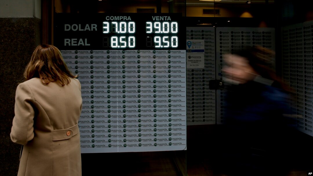 A woman looks at a sign announcing the price of the U.S. dollar and Brazilian real, in exchange for Argentine pesos, at a money exchange house in Buenos Aires, Argentina, Sept. 3, 2018. 