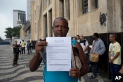In this May 31, 2017 photo, Jose Augusto shows his resume as he stands in line in search of work at the Labor Ministry in Rio de Janeiro, Brazil.