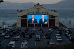 People watch from their vehicles as President Donald Trump, on left of video screen, and Democratic presidential candidate former Vice President Joe Biden speak during a Presidential Debate Watch Party in San Francisco, Oct. 22, 2020.
