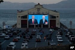 People watch from their vehicles as President Donald Trump, on left of video screen, and Democratic presidential candidate former Vice President Joe Biden speak during a Presidential Debate Watch Party in San Francisco, Oct. 22, 2020.