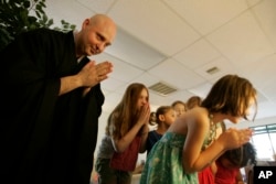 In this Sunday, June 19, 2011 photo, Rev. Jay Rinsen Weik bows with children after lighting an incense candle at the Toledo Zen Center in Holland, Ohio. The center has created a Sunday school and other programs to be especially welcoming to families.