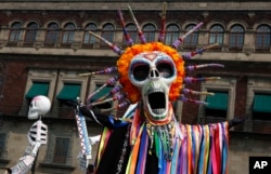 Performers in costume attend a Day of the Dead parade in Mexico City, Sunday, Oct. 27, 2019. (AP Photo/Ginnette Riquelme)