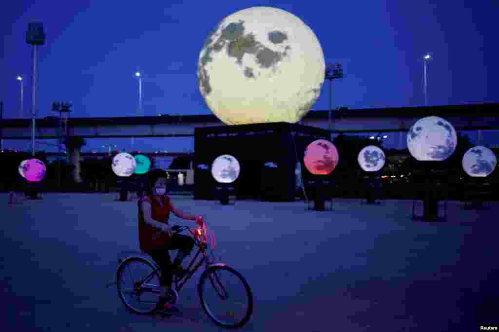 A woman rides a bike in a park installed with artificial full moons to celebrate upcoming Chuseok holiday, the Korean Thanksgiving Day, in Seoul, South Korea.