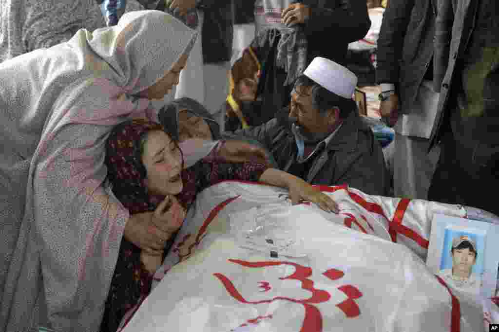 A Pakistani woman is comforted by other relatives while grieving over the body of her brother Mohammed Ali, who was killed in Saturday's bombing, in Quetta, Pakistan.