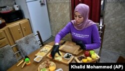 Fatima Ali prepares cheese-plate takeaway at her home kitchen in Baghdad, Iraq, Saturday, Nov. 28, 2020. (AP Photo/Khalid Mohammed)