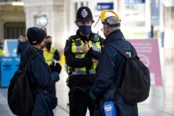 A member of the British Transport Police speaks with travelers at Waterloo Station in London, Dec. 20, 2020.