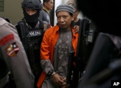 Aman Abdurrahman, tengah, dikawal para petugas kepolisian setibanya di persidangan di Pengadilan Negeri Jakarta Selatan, Jakarta, Indonesia, Jumat, 18 Mei 2018 (foto: AP Photo/Tatan Syuflana)